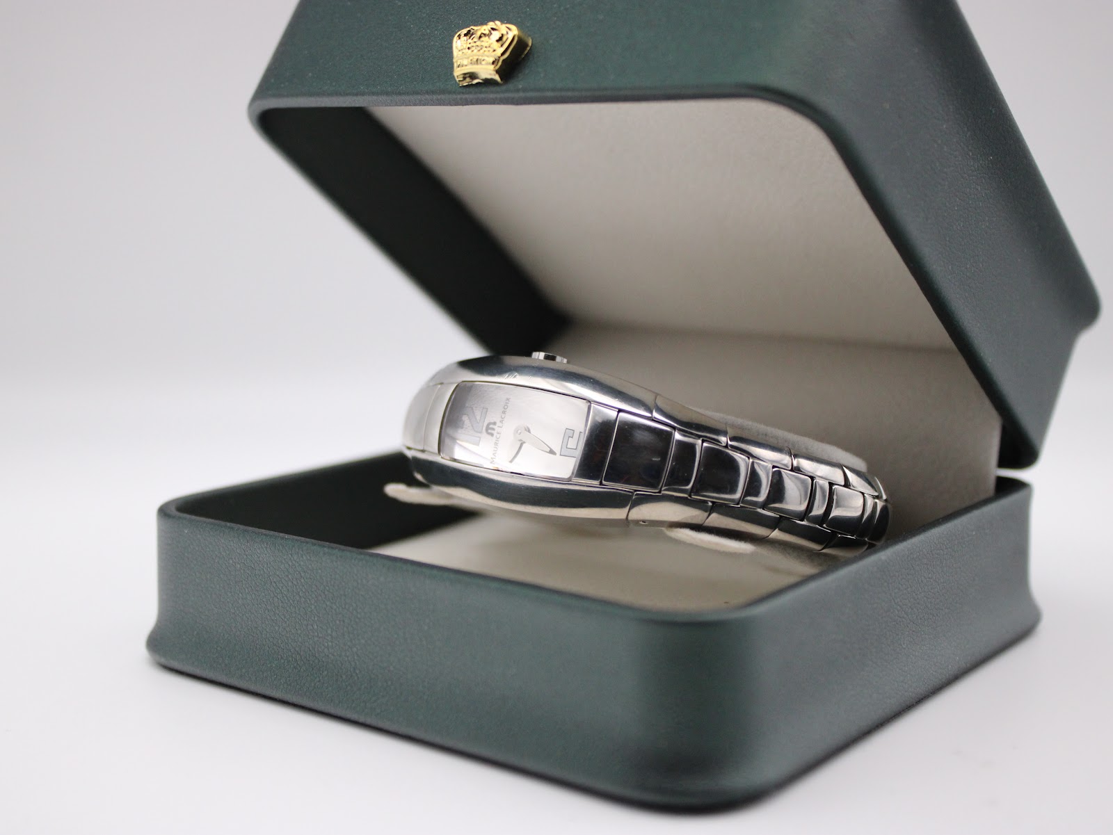Maurice Lacroix watch resting inside a dark green presentation box with a cream interior, displaying the watch's front.