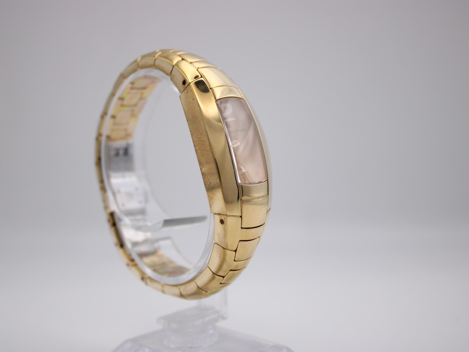 Opposite side view of the Maurice Lacroix watch on a stand, showcasing the continuous flow of the gold-plated bracelet.