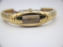 Another close-up of the watch from an elevated angle, focusing on the curved profile of the gold-plated case and the integrated bracelet.