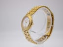 Angled side view of the gold-tone Maurice Lacroix watch and bracelet on a clear stand, showing the curved case profile.