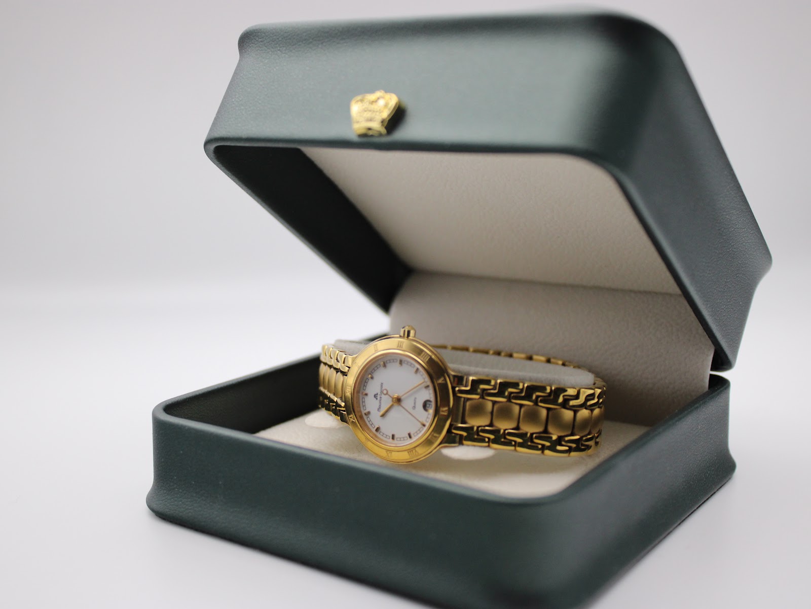 Maurice Lacroix watch resting in an open dark green presentation box with a cream-coloured interior.