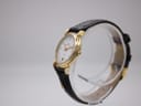 Angled side view of the Maurice Lacroix 72963 watch on a clear stand, showing the gold-plated case and crown.