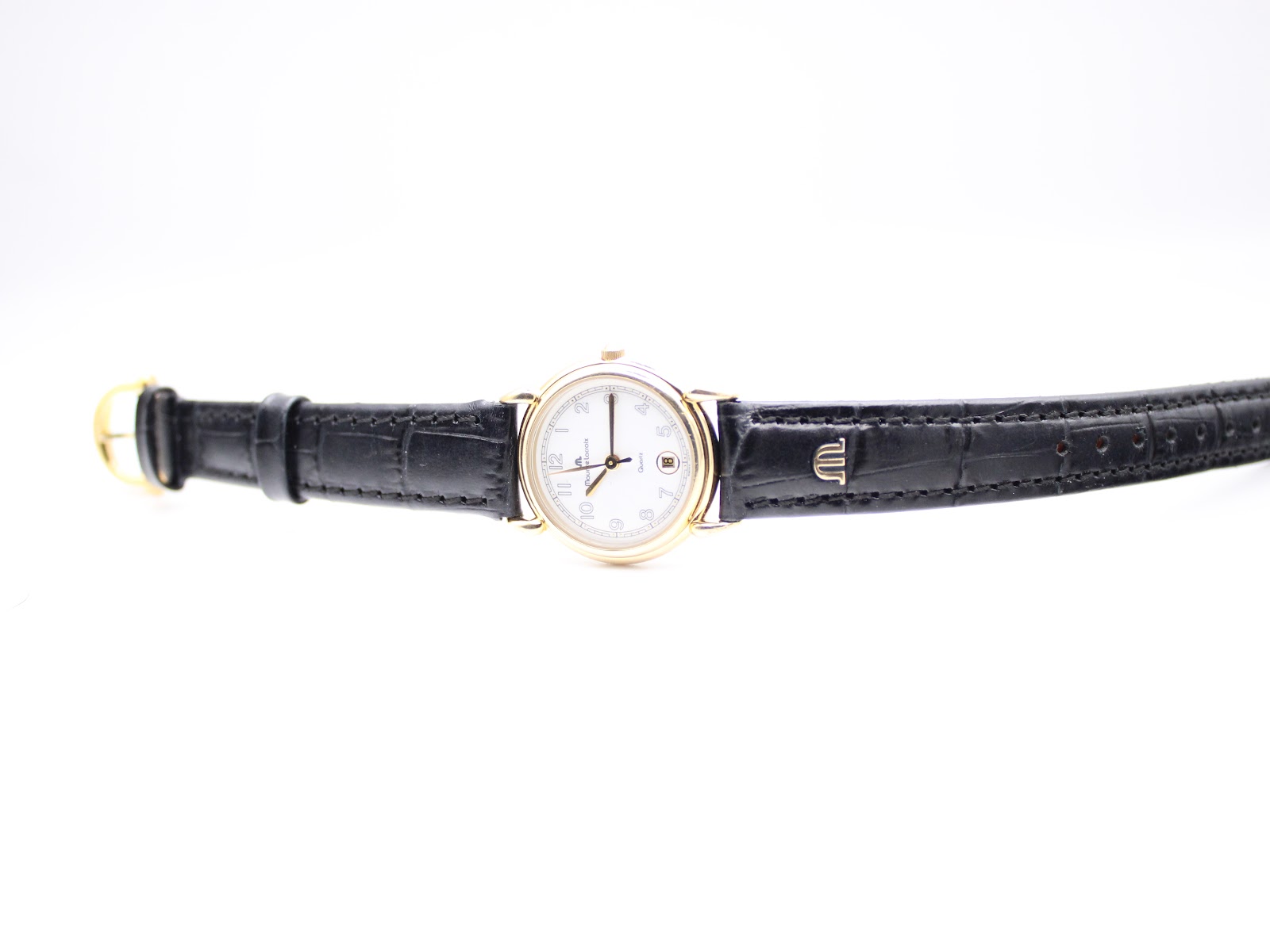 Overhead view of the Maurice Lacroix watch with its black leather strap laid flat, showcasing the full length and the gold buckle.