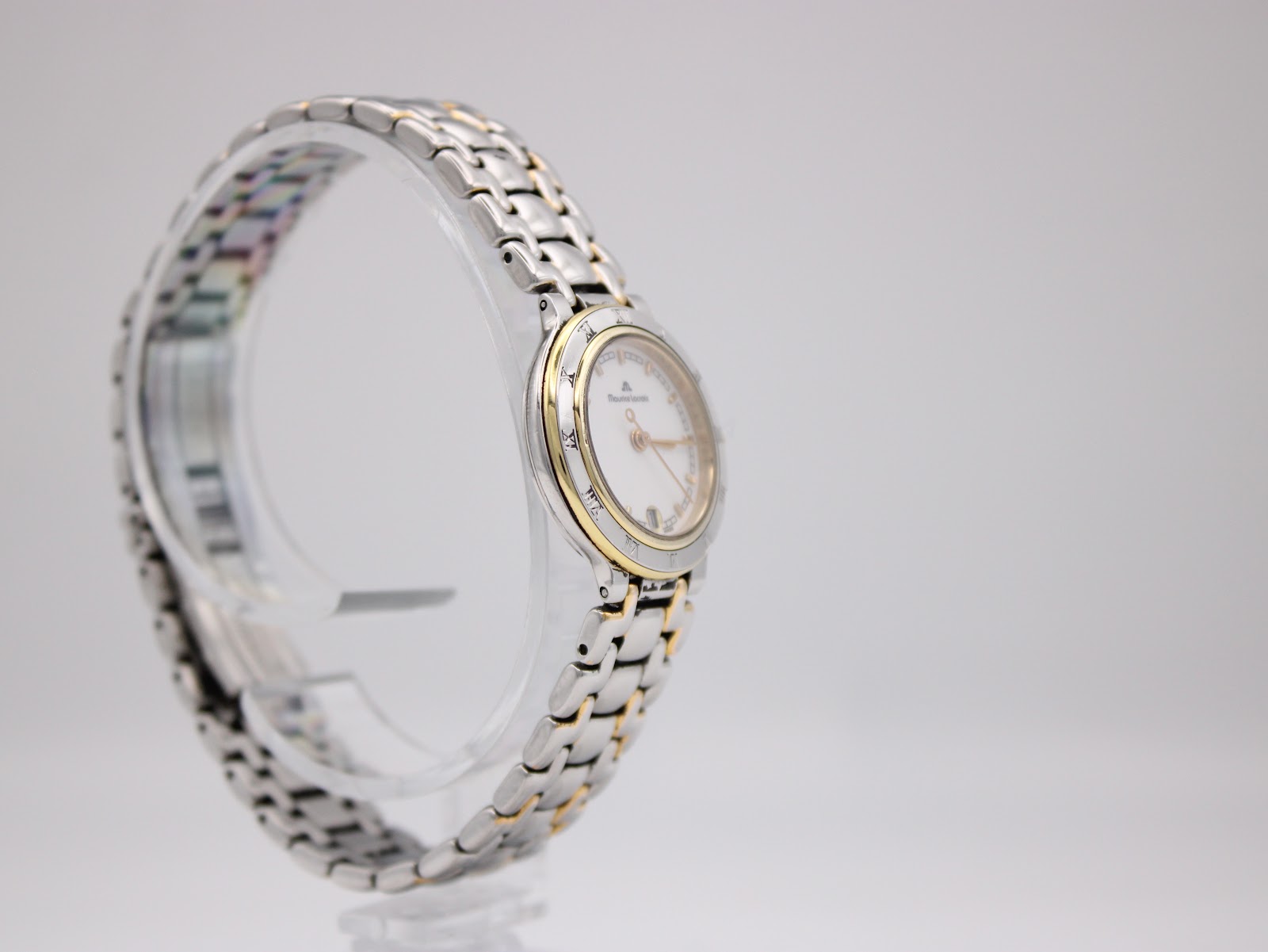 Another side-angle view of the watch on a display stand, highlighting the curve of the case and the two-tone link bracelet.