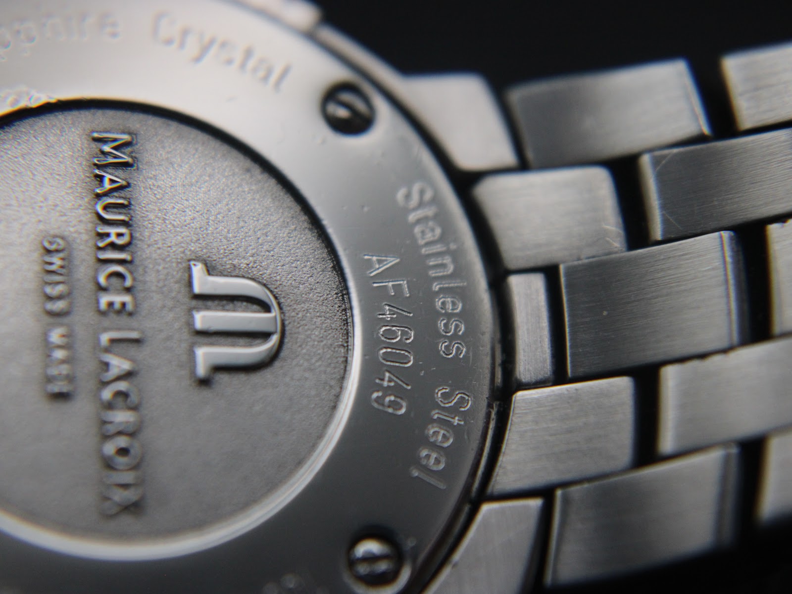 Angled close-up of the case back highlighting the serial number 'AF46049' and 'Stainless Steel' engraving.