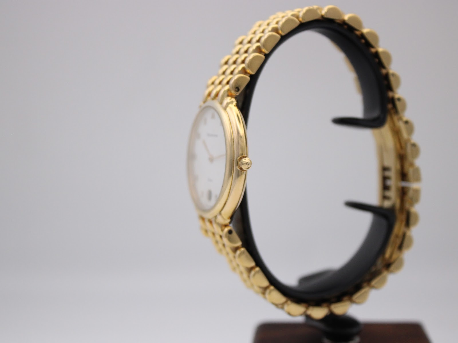 Side view of the Maurice Lacroix watch on a display stand, highlighting the profile of the gold electroplated case and bracelet.