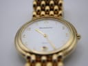 Angled close-up of the Maurice Lacroix watch dial, showing the white face, gold Arabic numerals, date window at 6, and 'Maurice Lacroix Quartz' text.