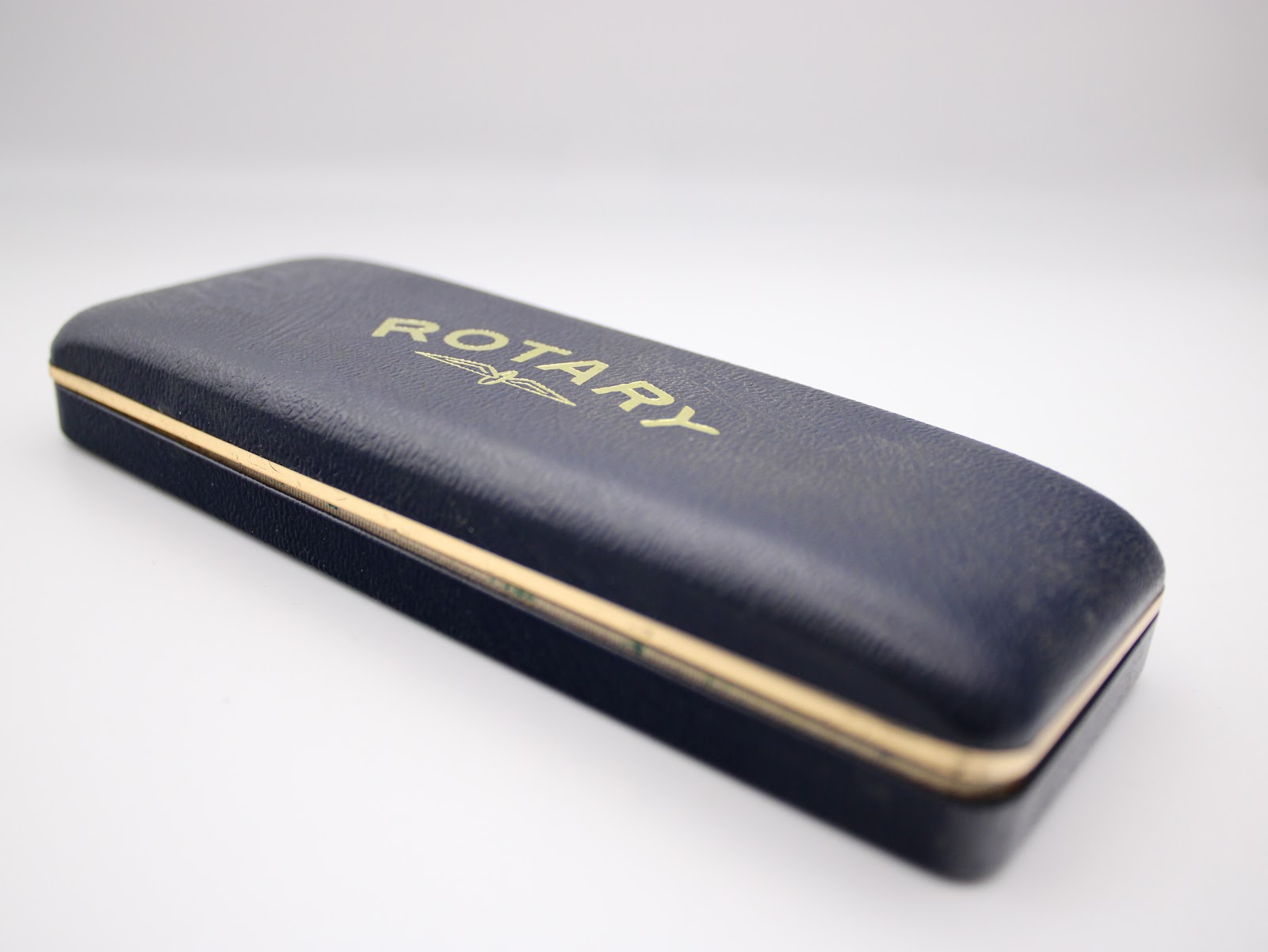 Closed view of the rectangular dark blue original Rotary presentation box with gold-tone accents and 'Rotary' logo.