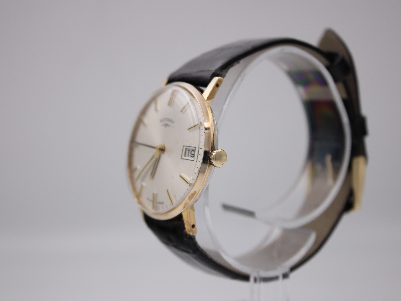 Side profile view of the Rotary watch on a display stand, highlighting the gold-plated case and original crown.