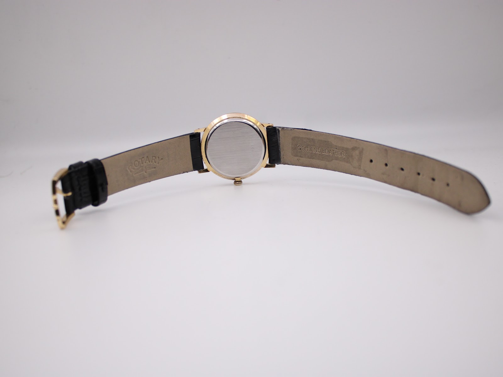 Back view of the Rotary watch and strap laid flat, showing the 'Rotary' embossing on the strap interior and case back.