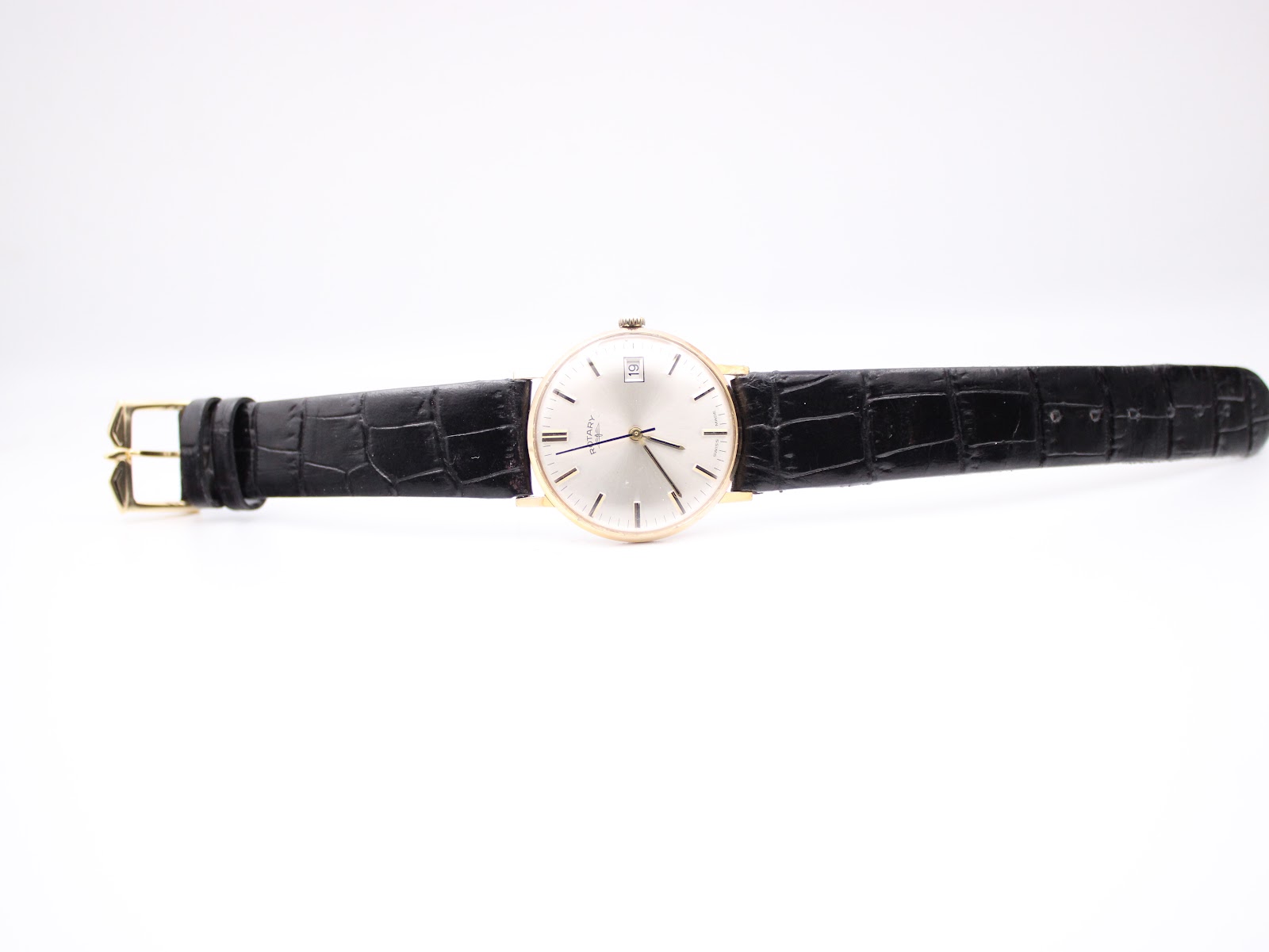 Overhead view of the entire Rotary watch with its black leather strap laid flat, showcasing the dial and gold-tone buckle.
