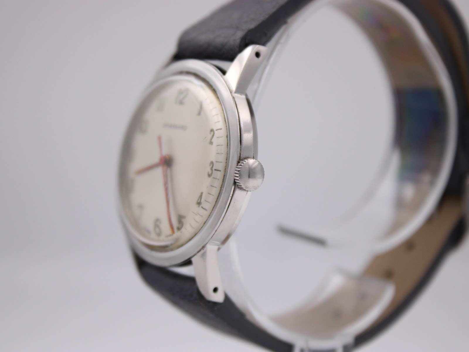 Side profile view of the Garrard watch on a stand, showing the stainless steel case, original crown, and domed acrylic crystal.
