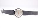 Full length view of the Garrard watch with its grey leather strap laid flat on a white background.
