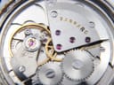Detailed macro shot of the Garrard manual wind mechanical movement, showing intricate gears, jewels, and the 'GARRARD' engraving.
