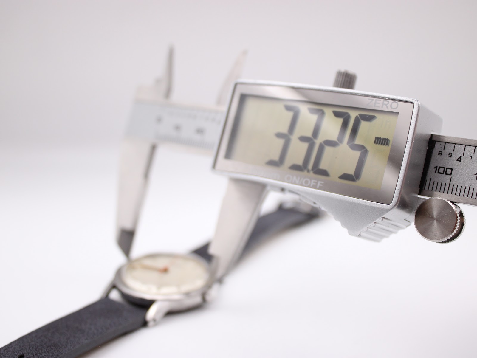 Digital caliper displaying a precise measurement of 33.25 mm across the Garrard watch case diameter.