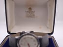 Interior of the original Garrard presentation box, lined with cream silk, showing 'By appointment to H.M. THE QUEEN' text, with the watch visible but blurred in the foreground.