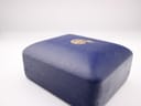 Exterior top view of the vintage navy blue Garrard presentation box with a gold crest.