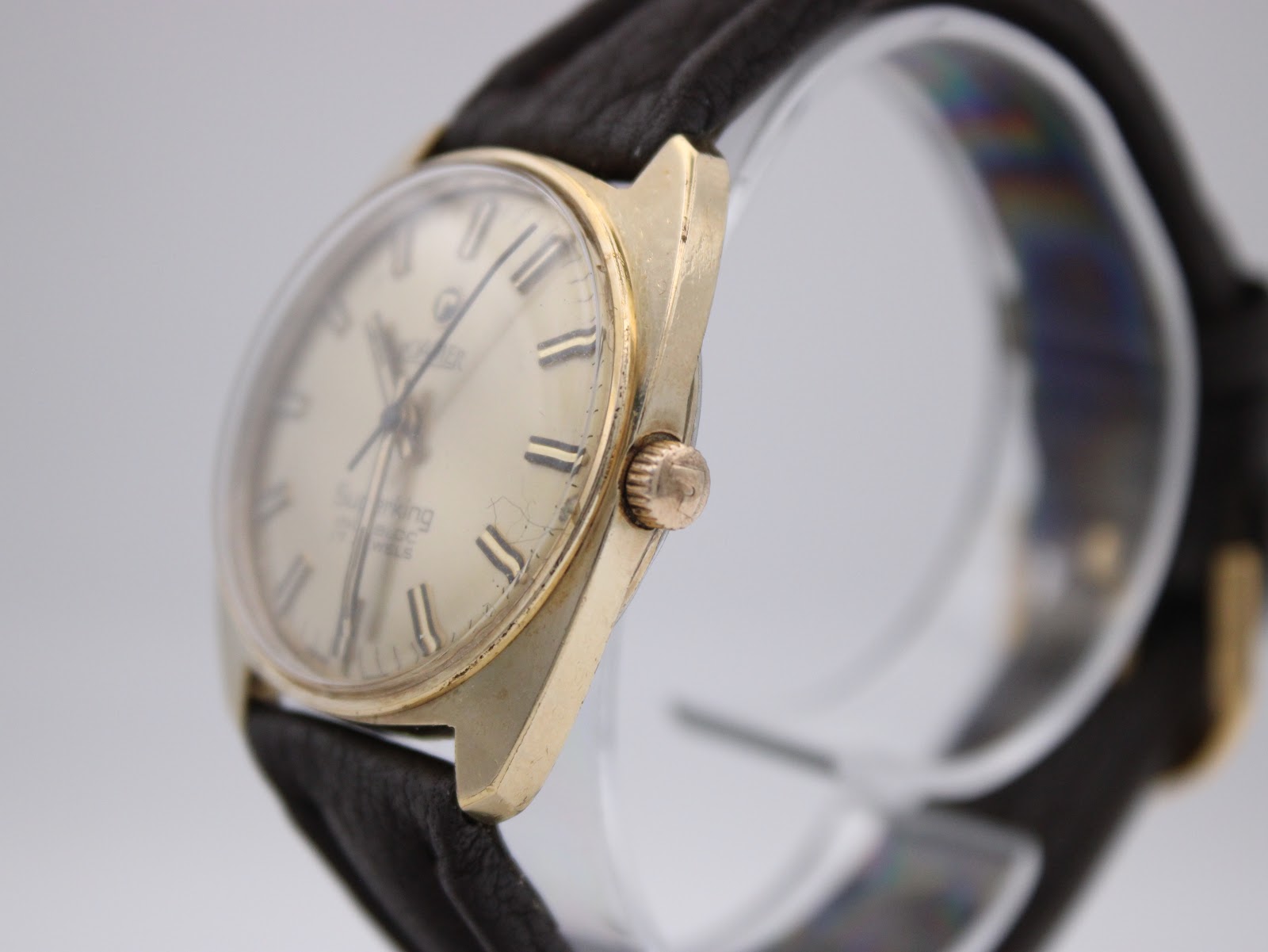 Angled side view of the Roamer Superking watch showing the gold-tone case, crown, and light wear on the side.