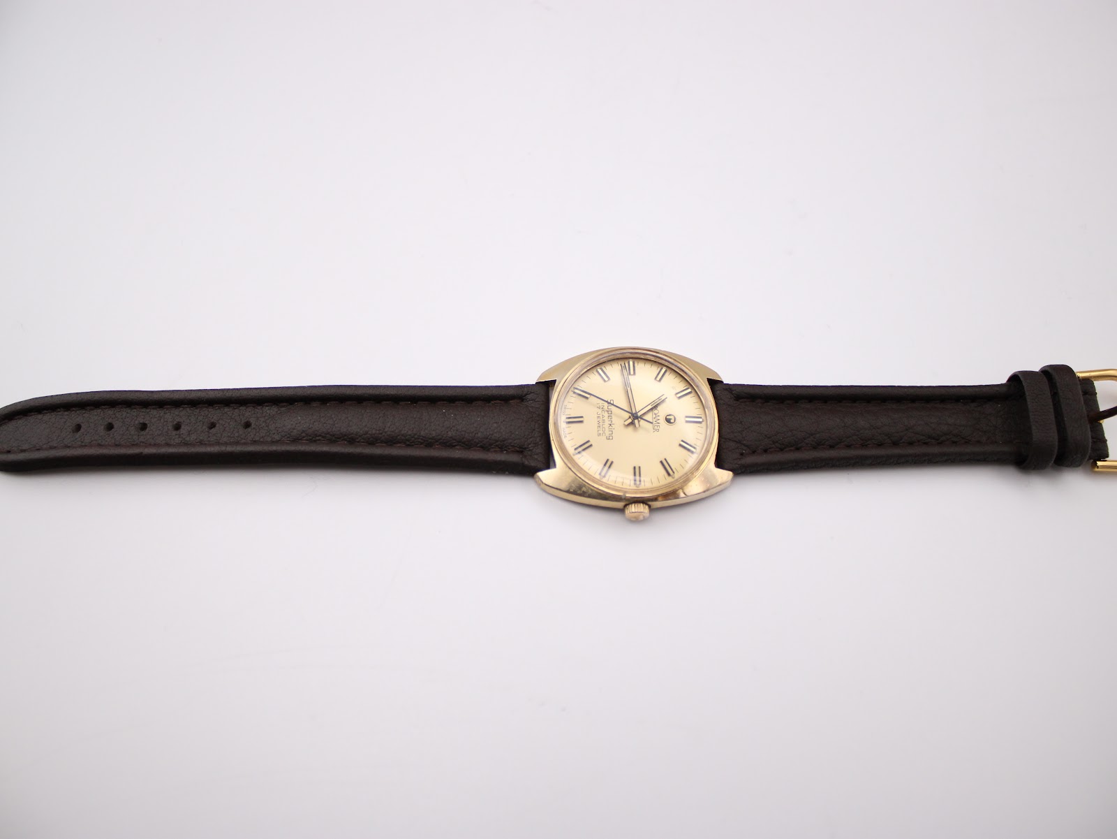 Top-down full view of the Roamer Superking watch with its dark brown leather strap laid flat on a white background.