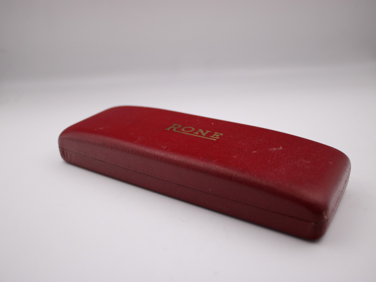 Top view of the closed original dark red Rone presentation box with "RONE" logo in gold lettering.