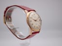 Angled side view of the Rone watch on a clear stand, showcasing the elegant lugs and gold-tone finish of the case.