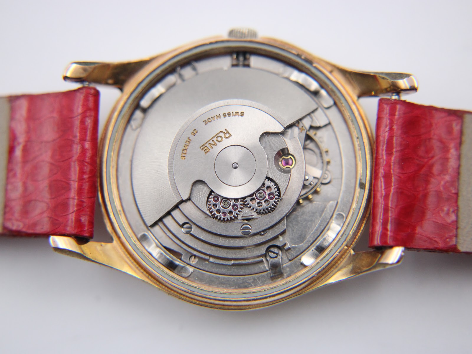Close-up of the Rone automatic movement, detailing the gears, jewels, and balance wheel, with "RONE SWISS MADE 25 JEWELS" visible.