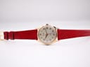 Full view of the Rone watch laid flat, displaying the red leather strap with gold-tone buckle and the cream dial.