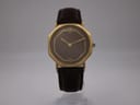 Front view of the Raymond Weil Genève octagonal gold-plated watch with a dark brown dial and brown leather strap on a stand.