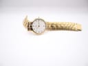 Overhead view of the Raymond Weil watch laid flat on a white surface, displaying the full length of the gold bracelet.