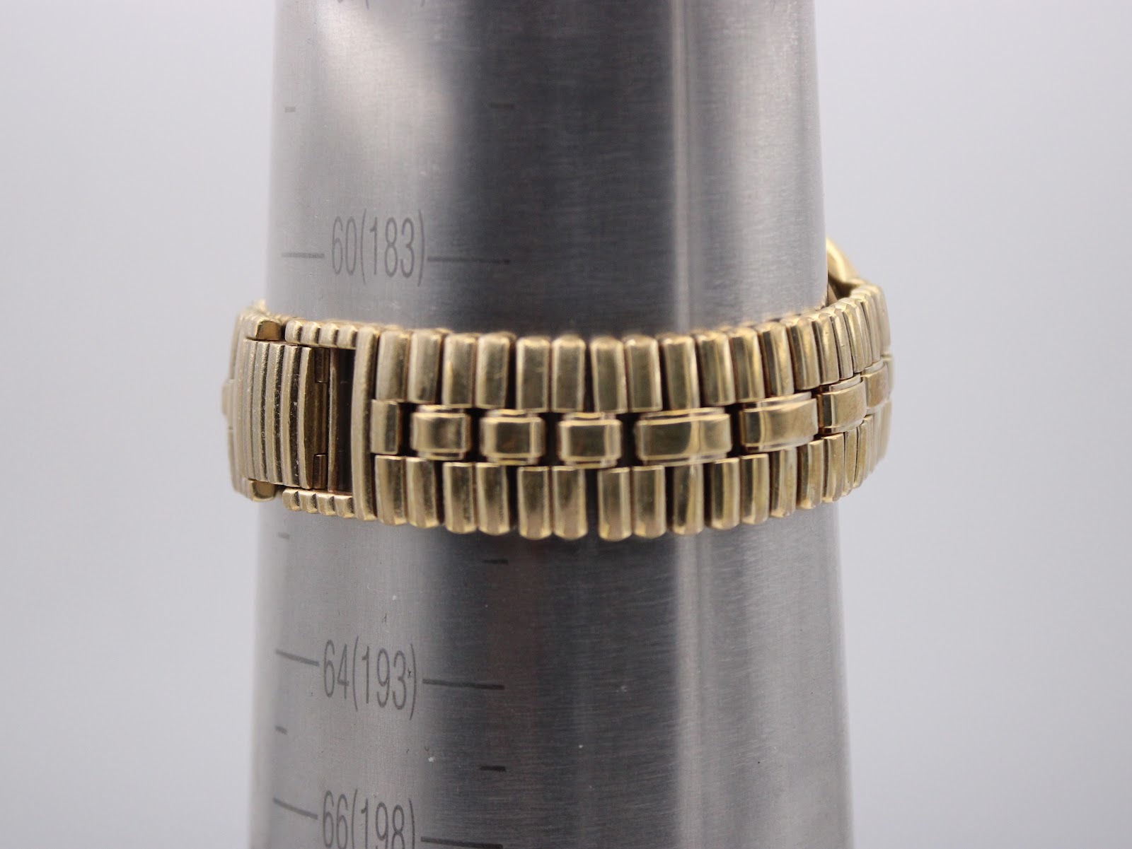 Close-up of the Raymond Weil gold bracelet on a wrist sizing gauge, indicating a maximum wrist size of approximately 6.2 inches / 15.7cm.