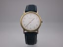 Front view of gold Certina quartz watch with white dial and blue leather strap on a display stand.