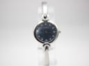 Front view of Michel Herbelin watch with blue mother-of-pearl dial and diamond markers on a clear stand.