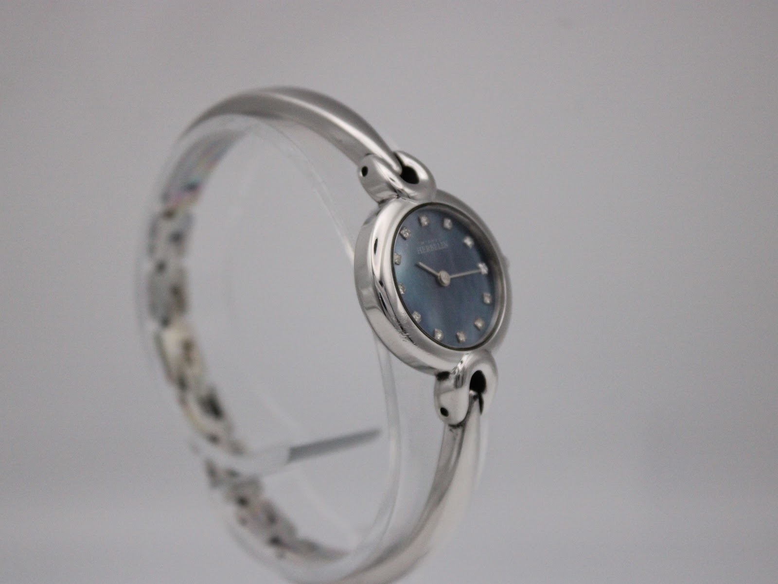 Slightly angled side view of the Michel Herbelin watch, highlighting the shiny stainless steel bangle and dial.