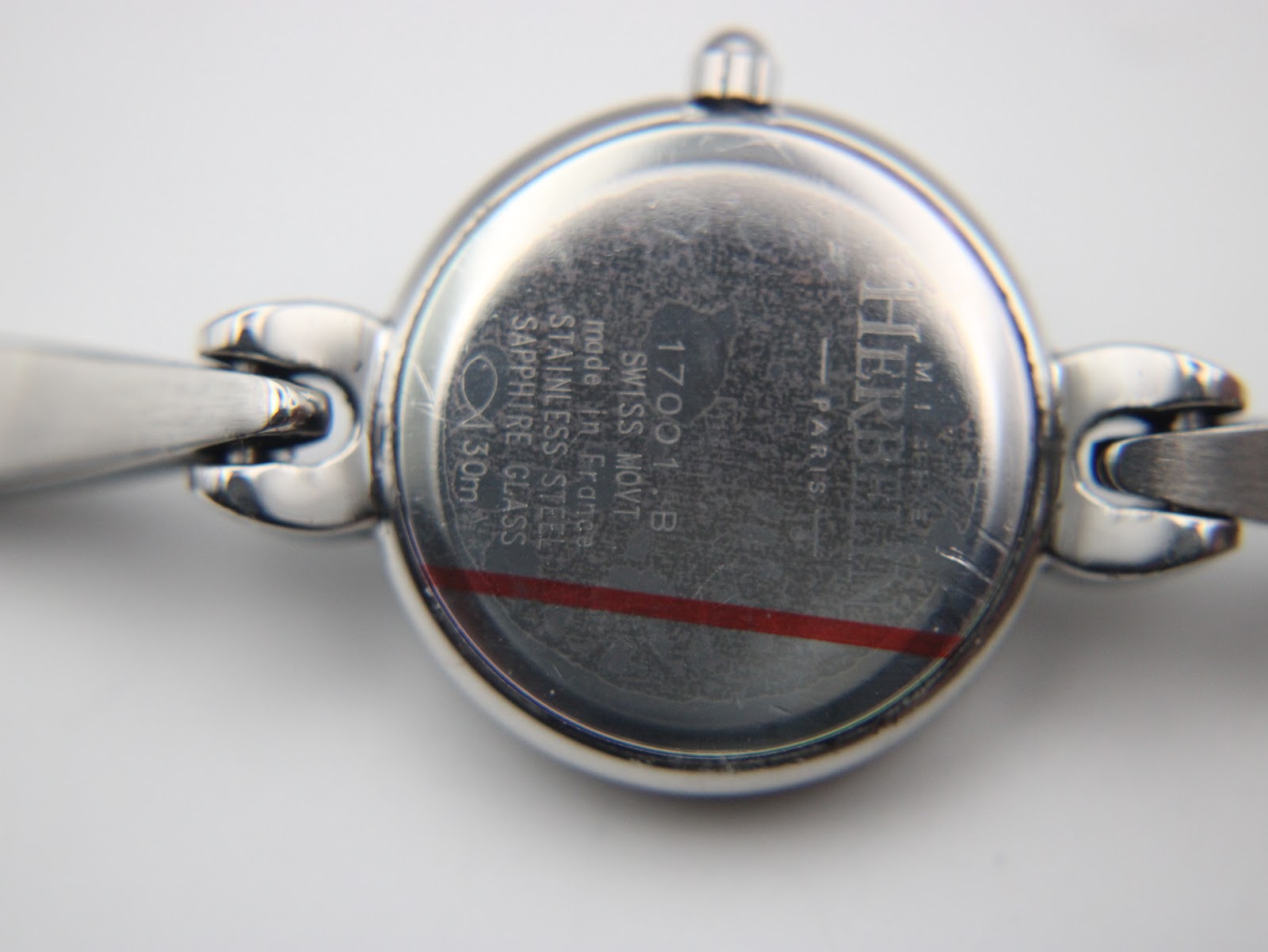 Close-up of the watch case back, showing "Michel Herbelin Paris", "Swiss Movt", "Stainless Steel", "Sapphire Glass", "30m", and model "17001/B".