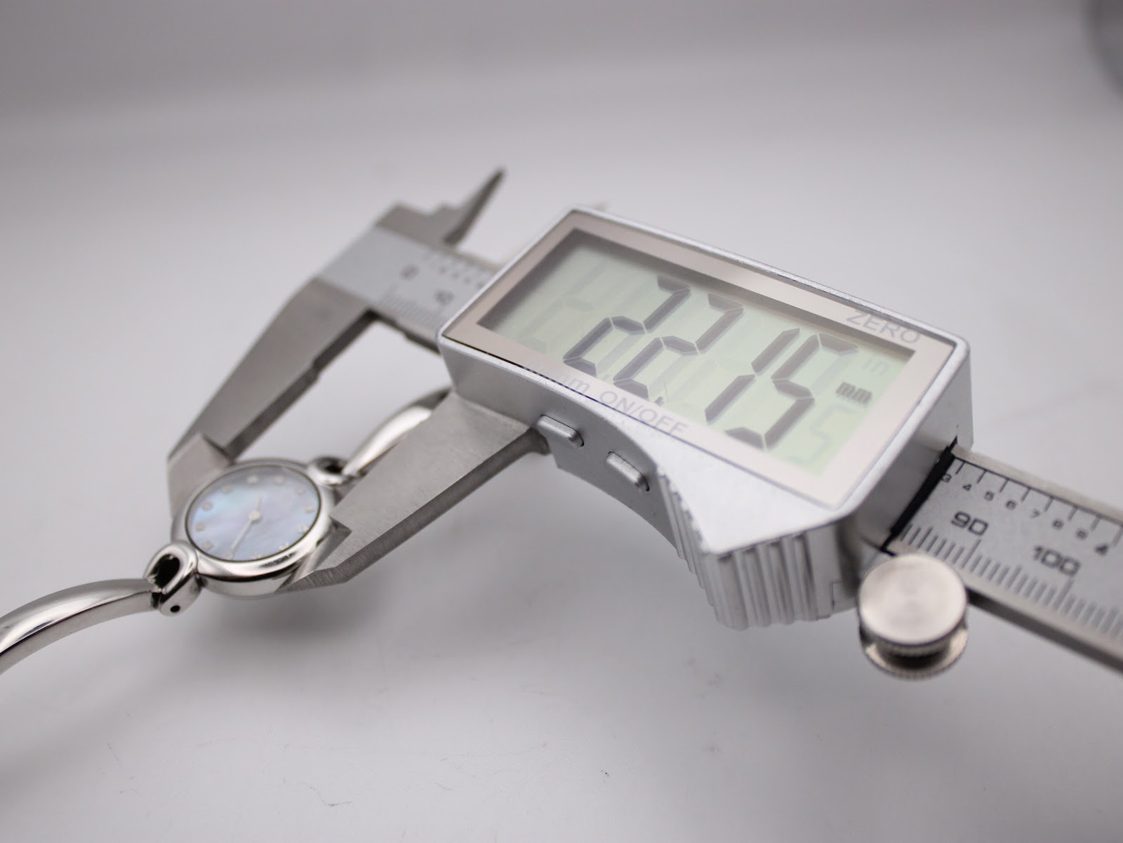 Digital caliper measuring the watch case diameter at 22.15 mm.