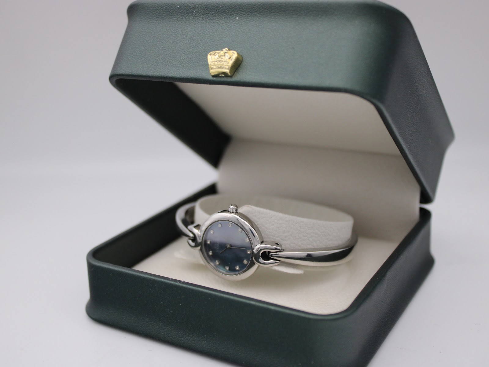 Michel Herbelin watch displayed inside an open dark green presentation box with a gold crown emblem.