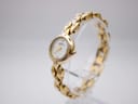 Angled view of Michel Herbelin ladies watch from the right, showcasing the gold-plated case and bracelet, with the white dial visible.