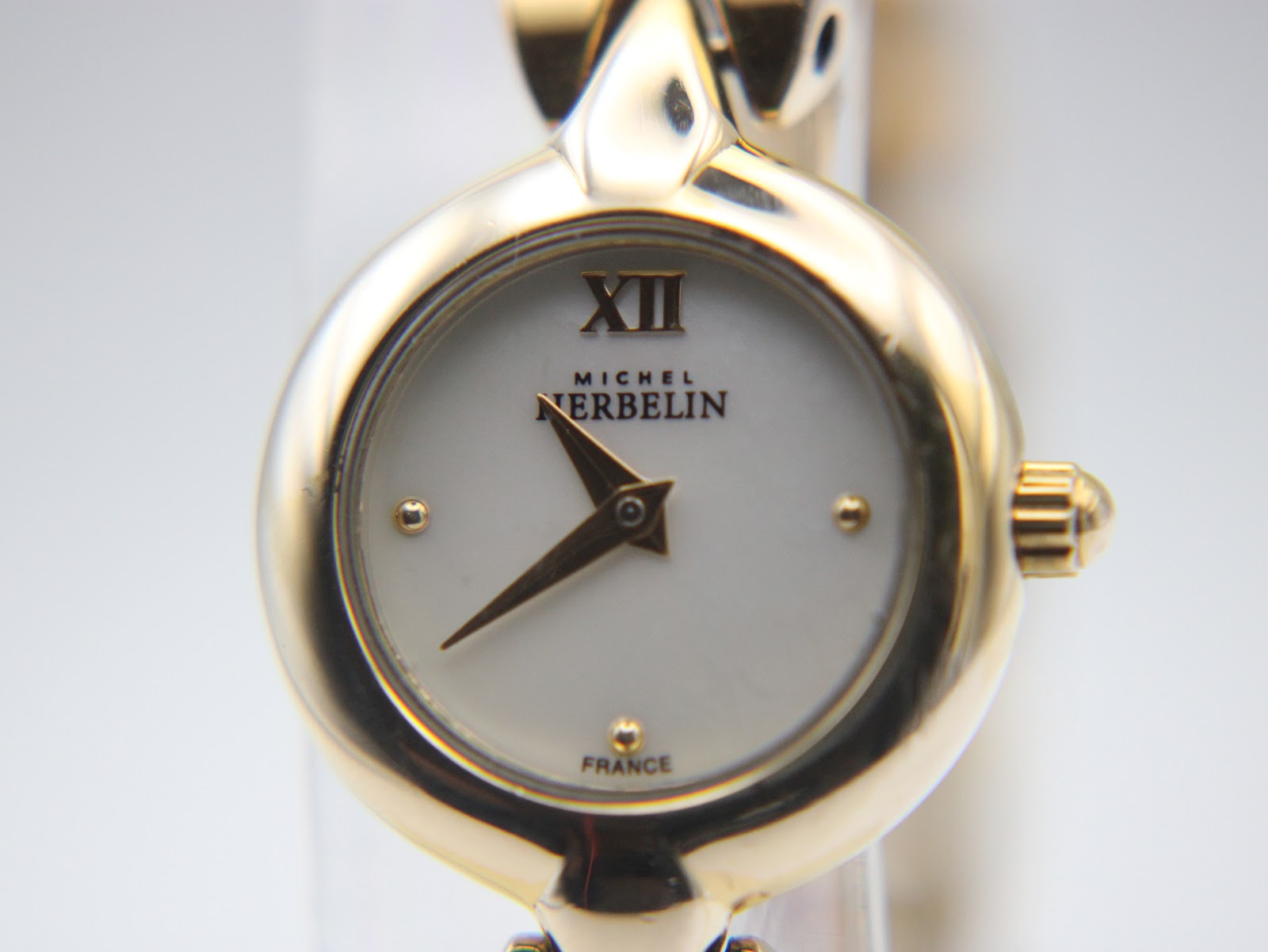 Close-up front view of the Michel Herbelin Paris dial, showing the white mother of pearl face, gold hands, XII Roman numeral, gold dot markers, and 'France' text.