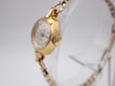 Side profile view of the gold Oris watch case and crown on a clear stand.