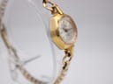 Angled view of the Oris watch showing the gold case, faceted crystal, and integrated bracelet.