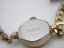 View of the watch case back, engraved "Lunette Plaqué G 10 Microns / Fond Acier Inox."