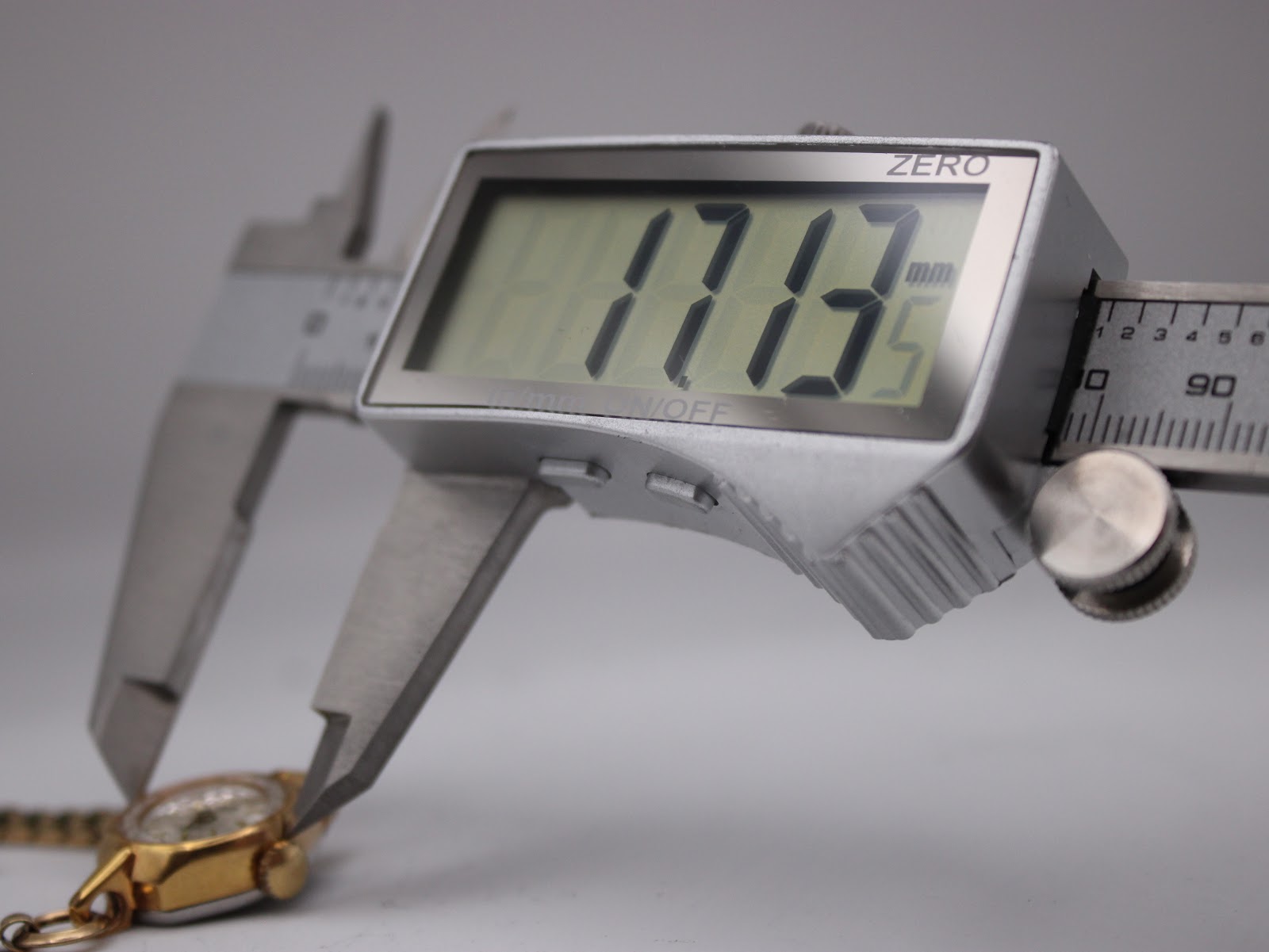 Digital caliper measuring the watch case diameter at 17.13 mm.