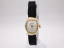 Front view of gold plated Bifora ladies' watch with silver dial and gold baton indices on a clear stand.