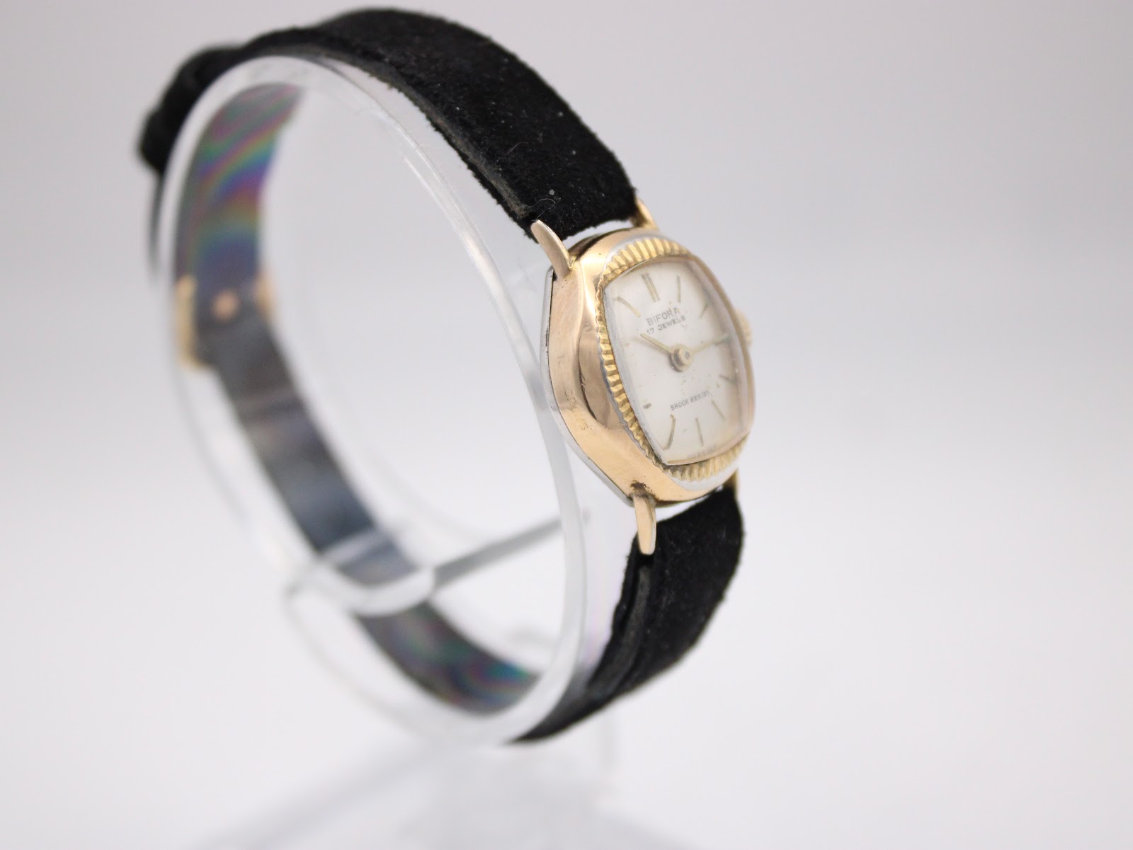 Another angled view of the Bifora watch, highlighting the vintage gold-plated case and black suede strap.