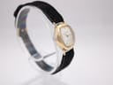 Another angled view of the Bifora watch, highlighting the vintage gold-plated case and black suede strap.