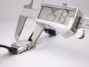 Digital caliper measuring the width of the Emporio Armani watch case, showing a precise measurement of 25.13mm.