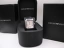 The Emporio Armani AR-0413 watch presented inside its original black Emporio Armani branded presentation box, with outer boxes in the background.