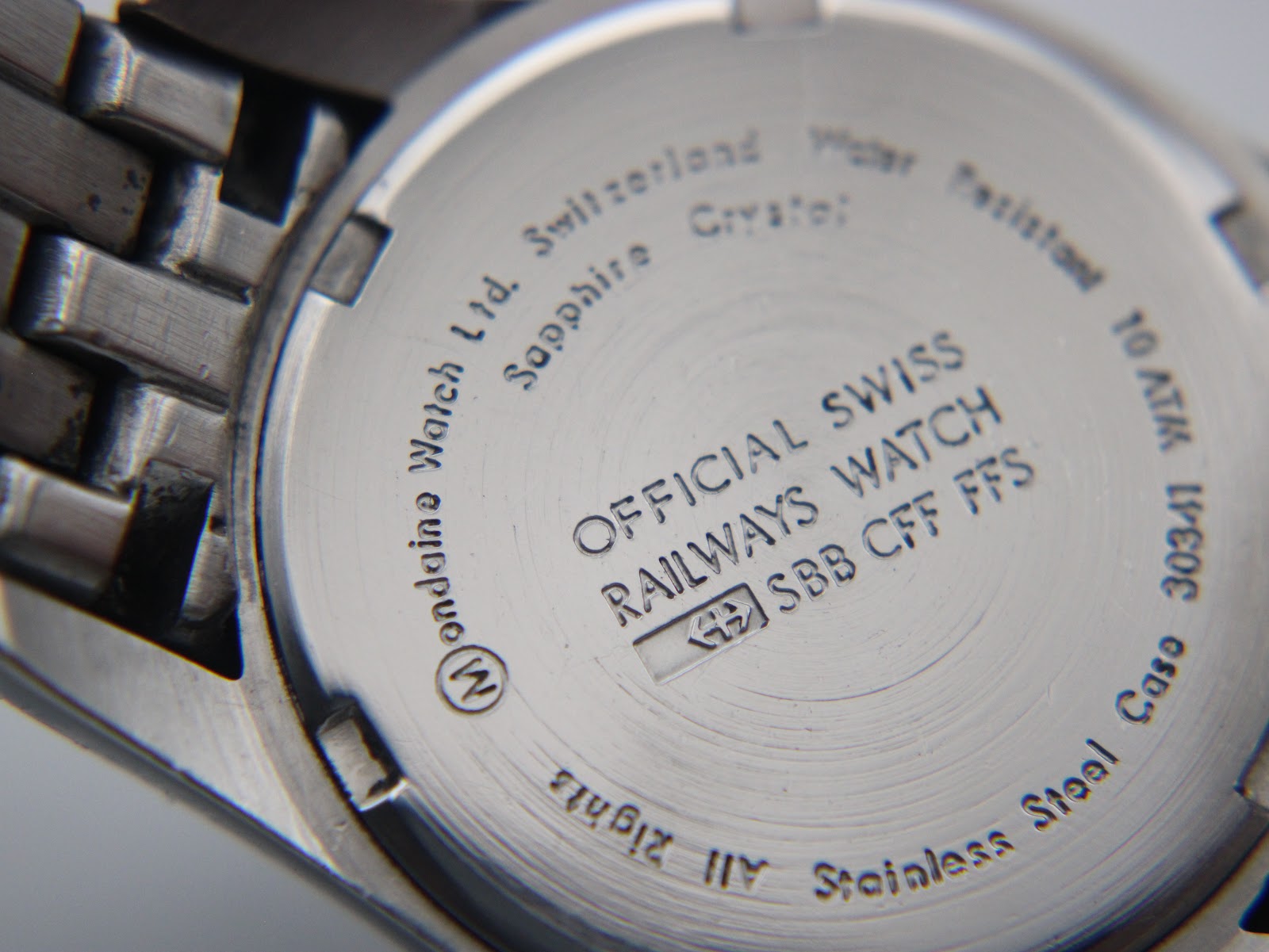 Close-up of the watch case back, showing engravings for "Official Swiss Railways Watch SBB CFF FFS", "Stainless Steel", "Sapphire Crystal", and "10 ATM Water Resistant".