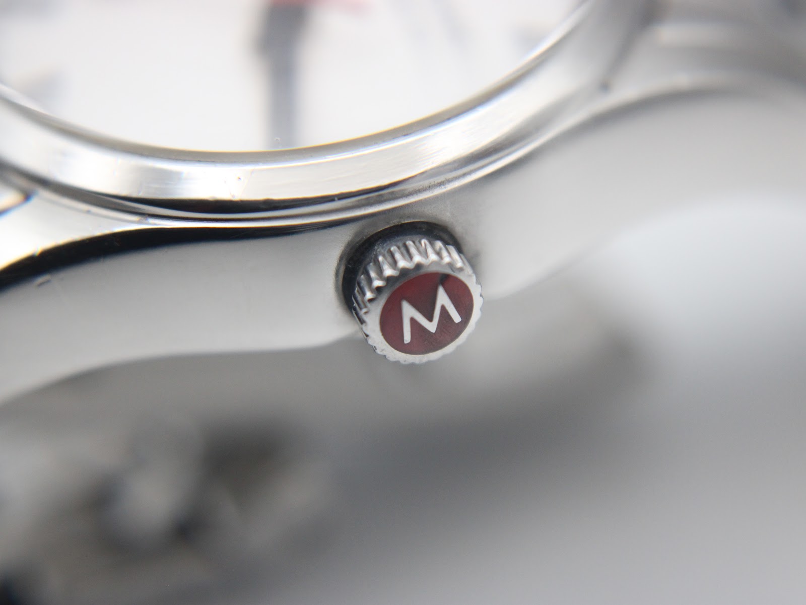 Macro shot of the red crown, prominently featuring the "M" logo for Mondaine.