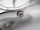 Macro shot of the red crown, prominently featuring the "M" logo for Mondaine.